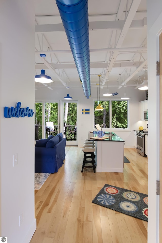 kitchen with light wood-style floors, appliances with stainless steel finishes, white cabinets, and a sink