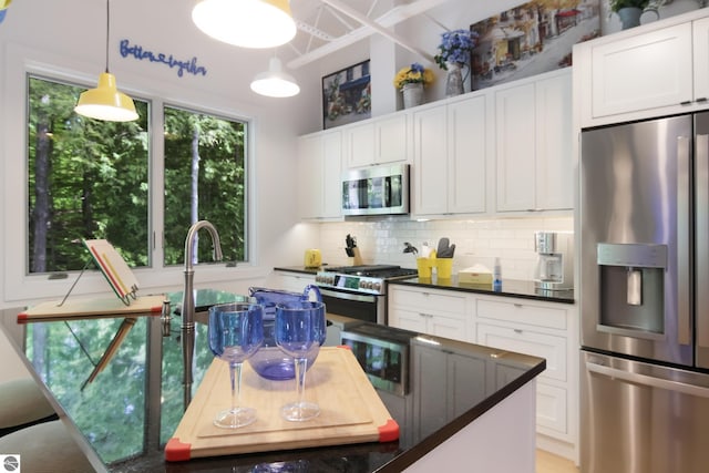 kitchen with dark countertops, appliances with stainless steel finishes, white cabinets, and backsplash