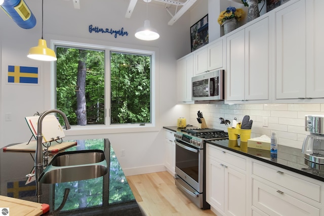 kitchen featuring a sink, appliances with stainless steel finishes, dark countertops, tasteful backsplash, and plenty of natural light