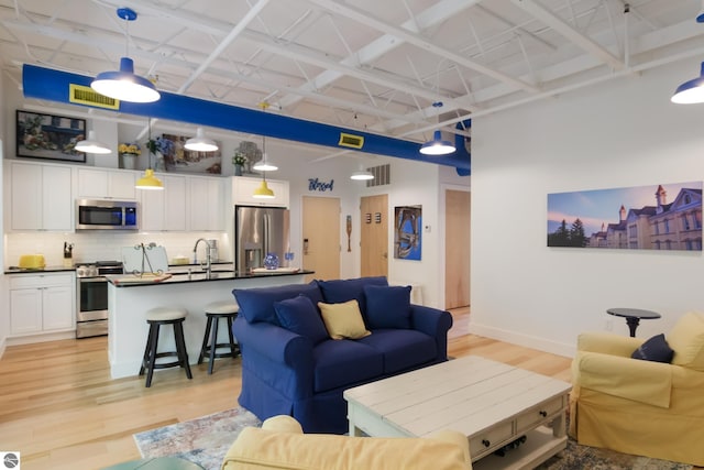 living area featuring light wood-type flooring, visible vents, and baseboards