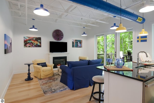 living room featuring a warm lit fireplace, wood finished floors, and baseboards