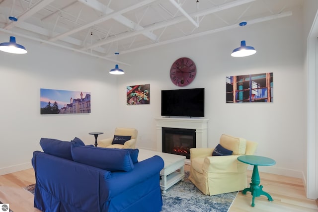 living room with a glass covered fireplace, wood finished floors, and baseboards