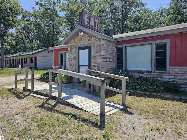 exterior space featuring a deck, stone siding, and a front yard