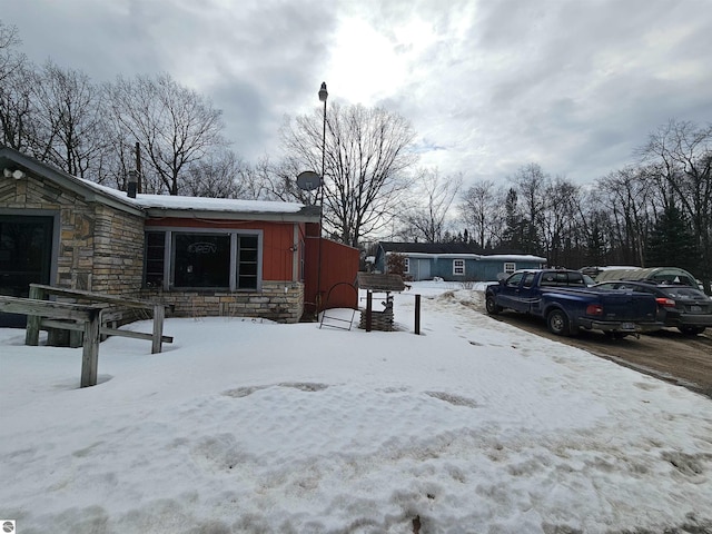 view of snow covered exterior with a garage and stone siding