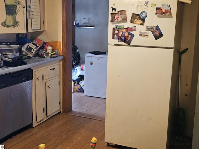 kitchen with wood finished floors, light countertops, stainless steel dishwasher, and freestanding refrigerator