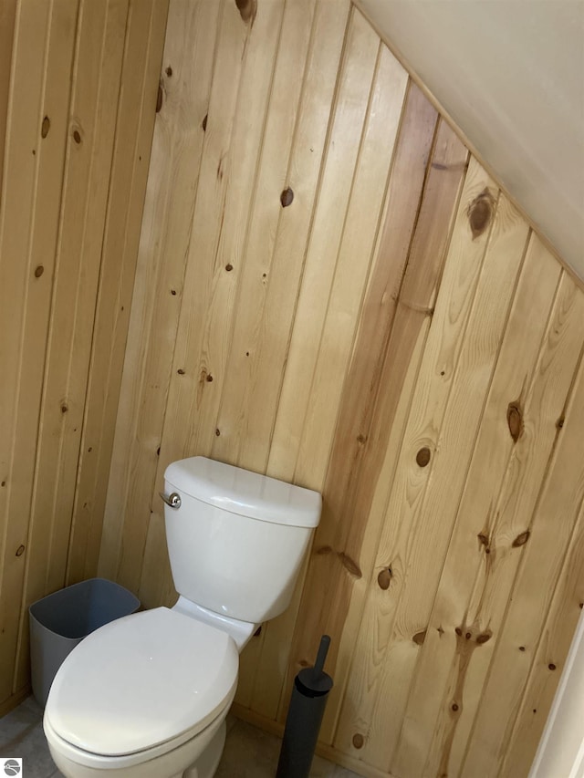 bathroom featuring toilet and wood walls