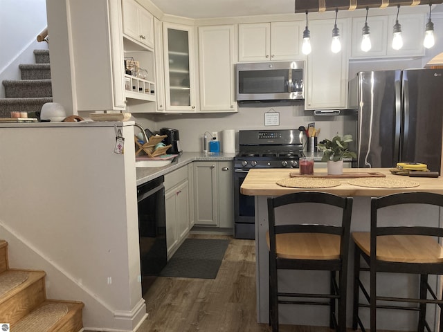 kitchen featuring stainless steel appliances, light countertops, dark wood-type flooring, white cabinets, and a sink