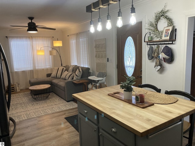 kitchen featuring a breakfast bar area, ornamental molding, freestanding refrigerator, wood counters, and wood finished floors