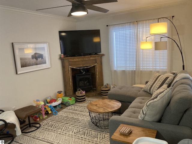 living area featuring a wood stove, crown molding, and ceiling fan