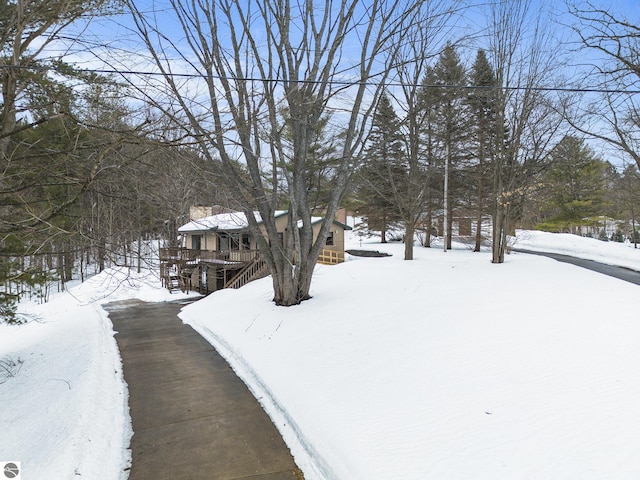 yard layered in snow featuring stairs and a wooden deck