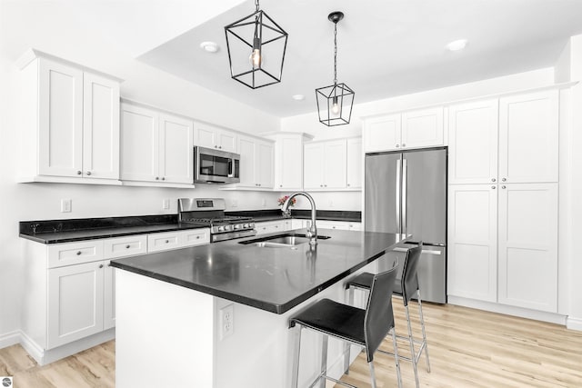 kitchen featuring dark countertops, appliances with stainless steel finishes, light wood-type flooring, and a sink