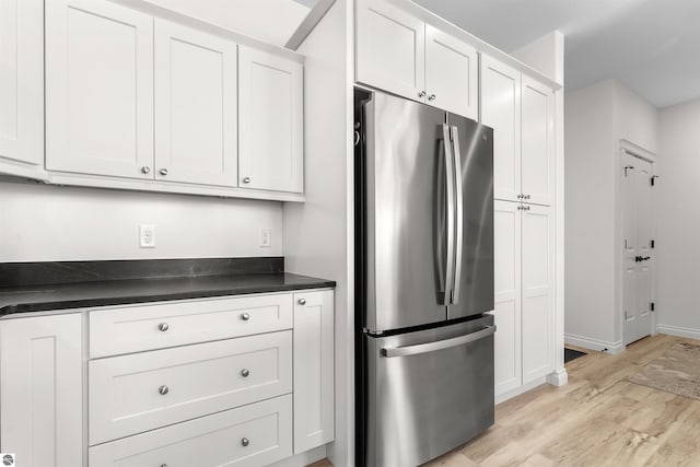 kitchen featuring dark countertops, light wood-style floors, white cabinetry, and freestanding refrigerator