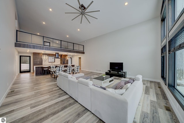 living room with light wood-style flooring, baseboards, and a towering ceiling