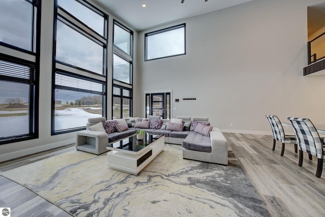 living room with a high ceiling, wood finished floors, baseboards, and a wealth of natural light