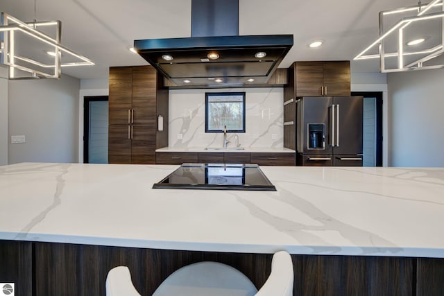 kitchen with black electric stovetop, decorative backsplash, high quality fridge, island range hood, and a sink