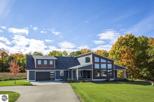 view of front of home with a front yard, a garage, a sunroom, and aphalt driveway