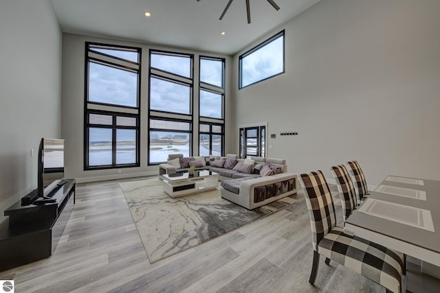 living area with light wood finished floors, recessed lighting, and a towering ceiling