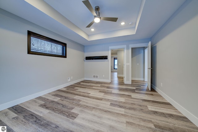 unfurnished bedroom featuring recessed lighting, baseboards, a raised ceiling, and light wood-style floors