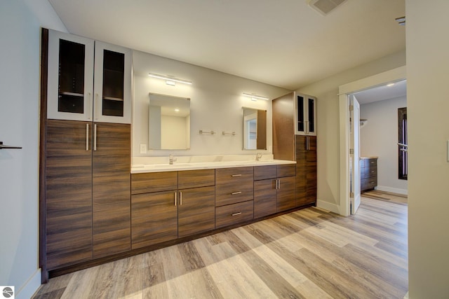 full bath with wood finished floors, visible vents, baseboards, double vanity, and a sink