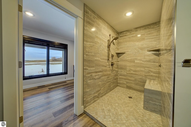 full bath with recessed lighting, baseboards, tiled shower, and wood finished floors