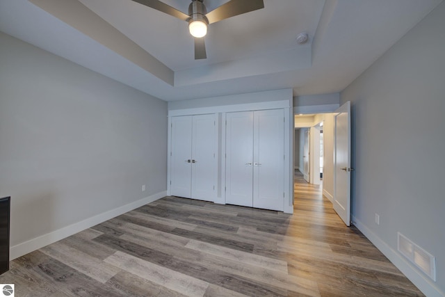 unfurnished bedroom with a tray ceiling, baseboards, and visible vents