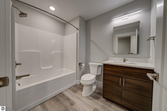 full bath featuring vanity, wood finished floors, baseboards,  shower combination, and toilet