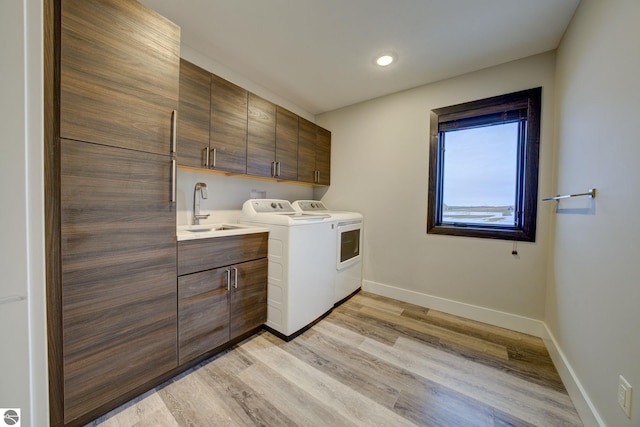 laundry room with baseboards, cabinet space, independent washer and dryer, and a sink