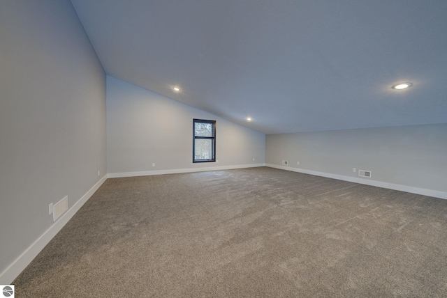 unfurnished room featuring vaulted ceiling, carpet, visible vents, and baseboards