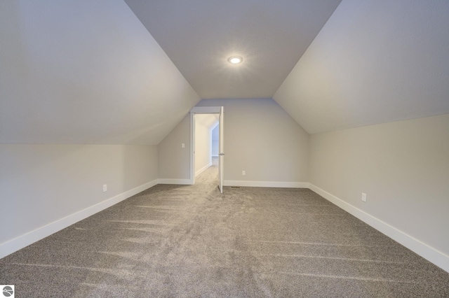 additional living space with vaulted ceiling, baseboards, and carpet floors