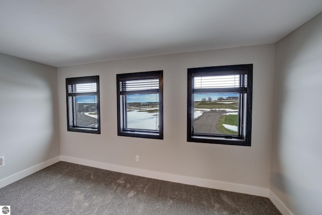 empty room with baseboards and dark colored carpet