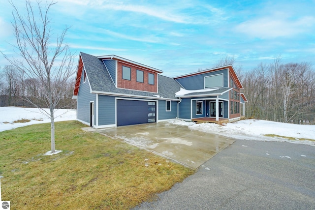 view of front facade with driveway, a porch, a yard, a shingled roof, and a garage