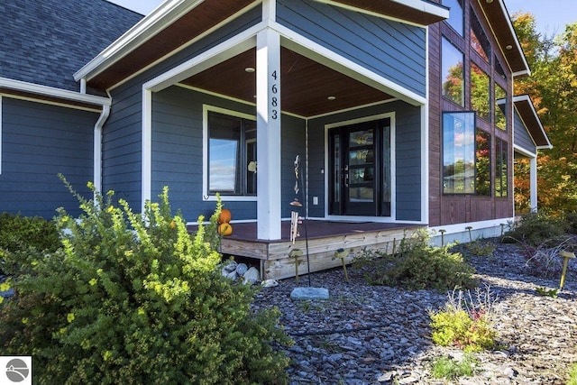 view of exterior entry featuring a porch and roof with shingles