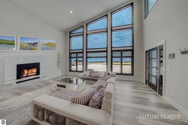 living room with high vaulted ceiling, wood finished floors, baseboards, and a premium fireplace