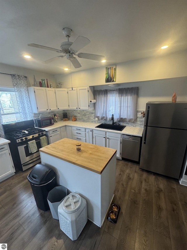 kitchen with stainless steel appliances, a sink, white cabinetry, dark wood-style floors, and tasteful backsplash