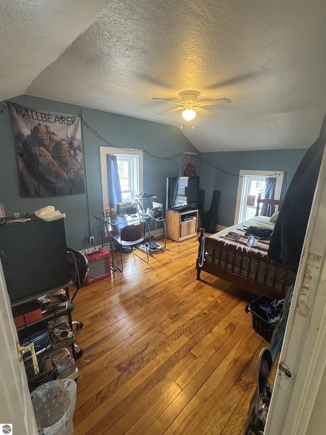 bedroom featuring light wood finished floors, multiple windows, and vaulted ceiling