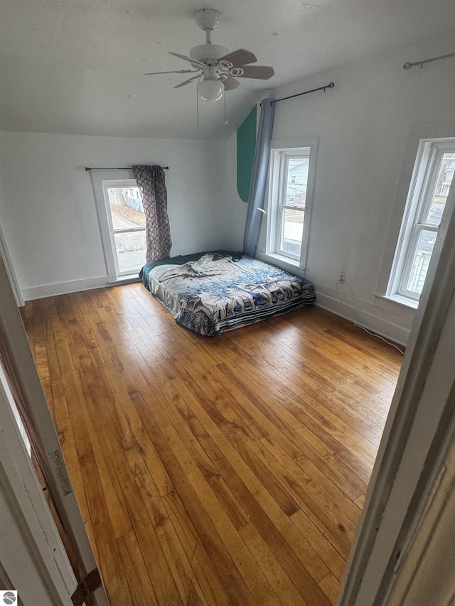 unfurnished bedroom featuring lofted ceiling, ceiling fan, hardwood / wood-style flooring, and baseboards