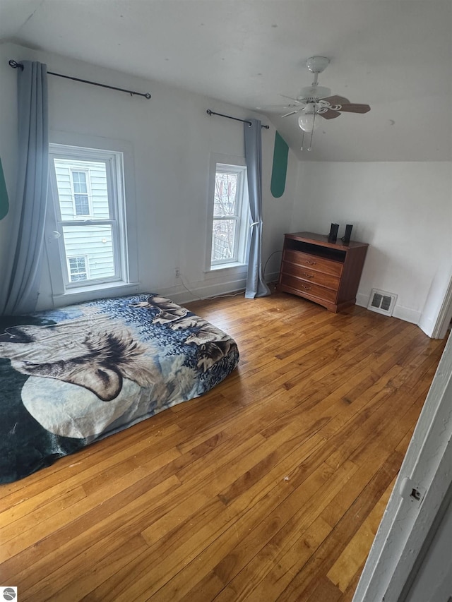 bedroom with baseboards, visible vents, lofted ceiling, ceiling fan, and hardwood / wood-style floors