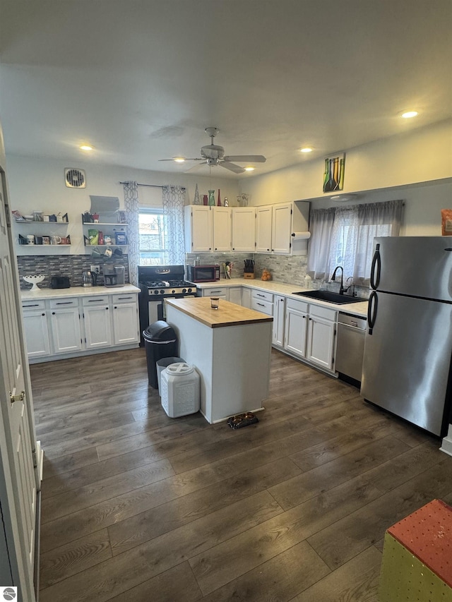 kitchen with dark wood finished floors, butcher block counters, appliances with stainless steel finishes, white cabinetry, and a sink