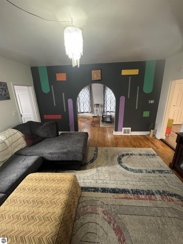 living room featuring wood finished floors, visible vents, and a notable chandelier