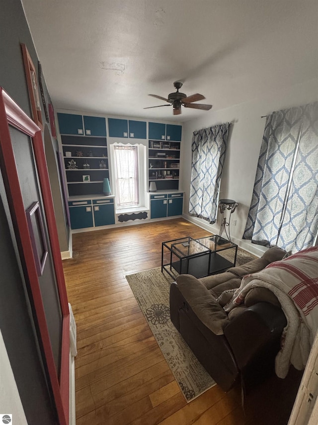 living area with ceiling fan, hardwood / wood-style floors, and built in shelves