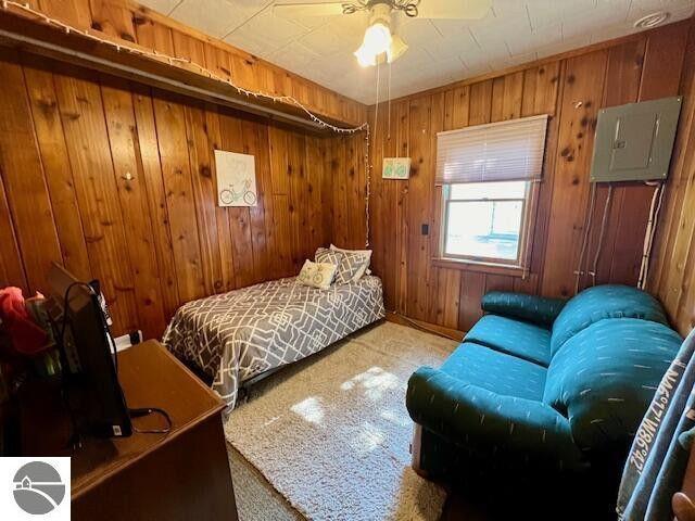 bedroom featuring electric panel and wood walls