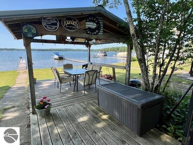 wooden terrace with a gazebo, outdoor dining space, and a water view