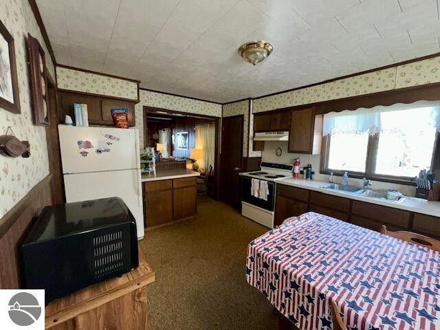 kitchen with light countertops, electric range, freestanding refrigerator, under cabinet range hood, and wallpapered walls