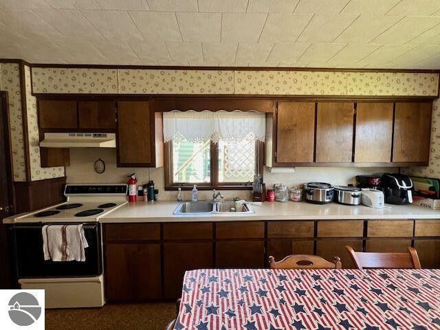 kitchen with light countertops, a sink, white electric range oven, and under cabinet range hood