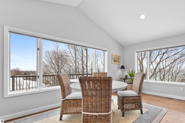 dining room featuring vaulted ceiling, light wood finished floors, visible vents, and a healthy amount of sunlight