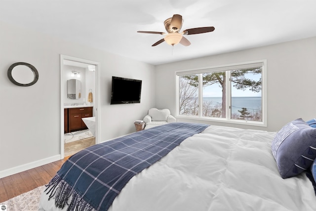 bedroom with light wood-type flooring, baseboards, a ceiling fan, and ensuite bathroom