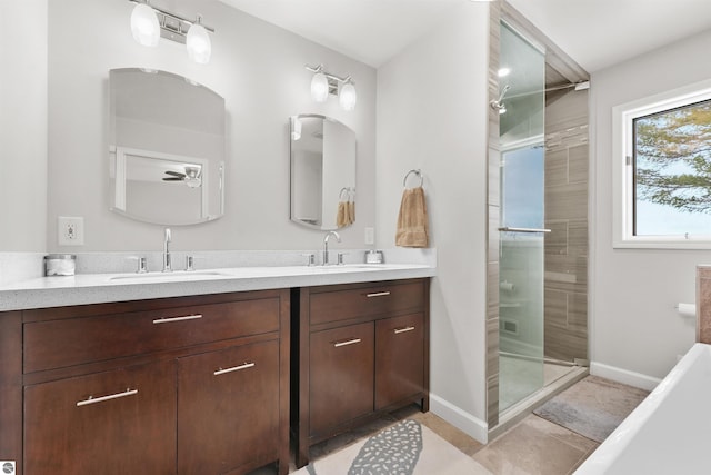 bathroom with double vanity, a stall shower, baseboards, and a sink