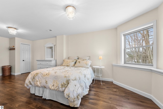 bedroom with visible vents, baseboards, and wood finished floors