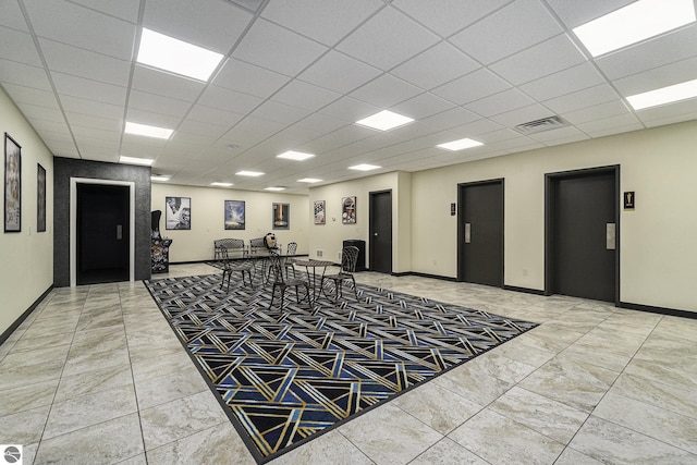 interior space with baseboards, a paneled ceiling, visible vents, and elevator