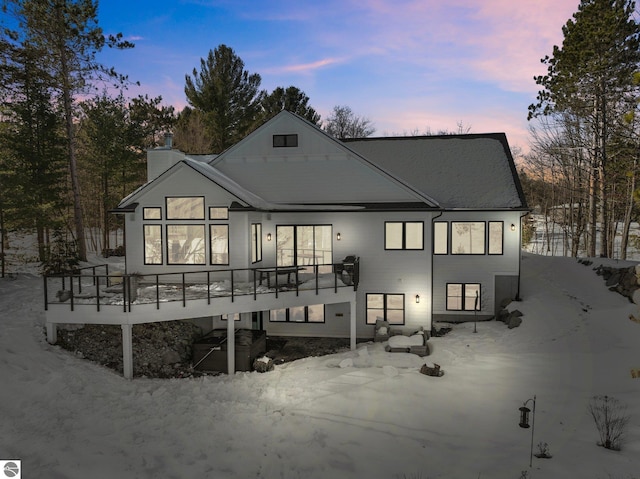 back of property at dusk featuring a chimney and a deck